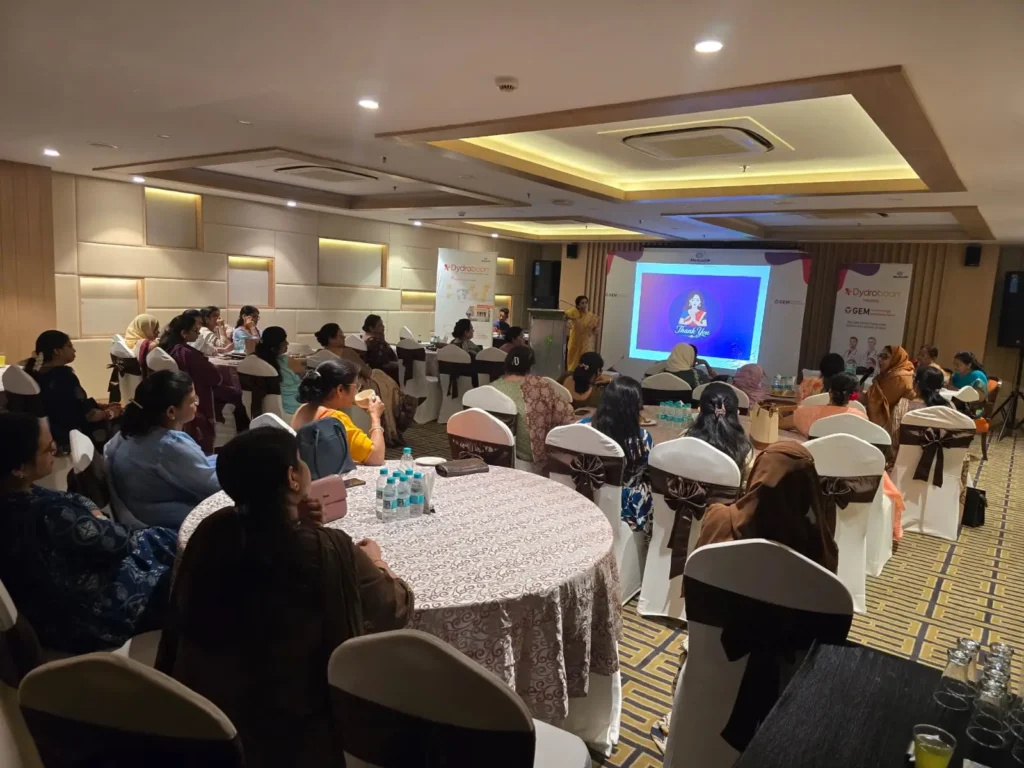 Audience attending a healthcare awareness seminar in a conference hall, watching a medical presentation on a projector screen.